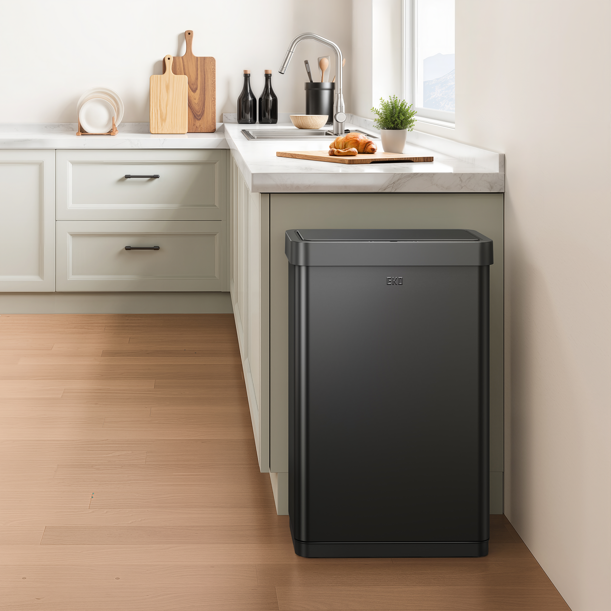 EKO trash can next to a modern kitchen counter, surrounded by light wood cabinetry and appliances.