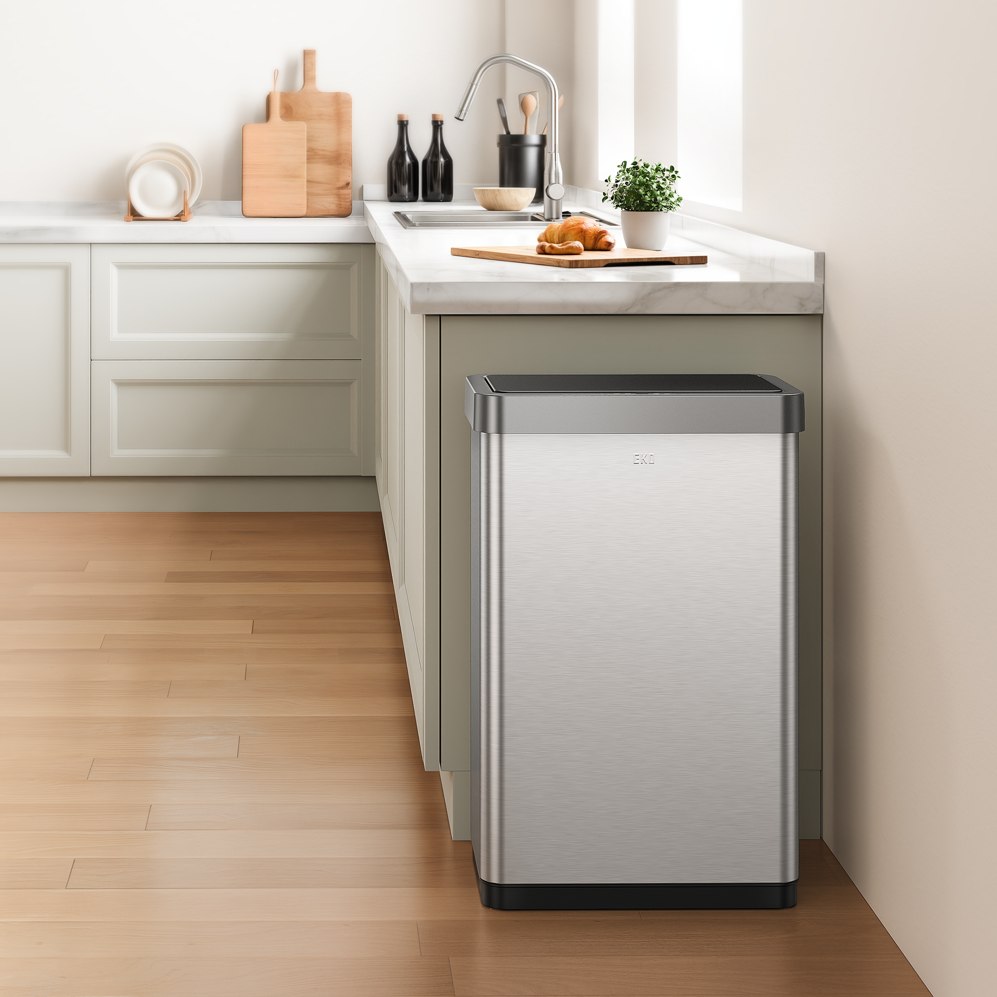 EKO stainless steel trash can in a kitchen setting with a countertop and cabinets.