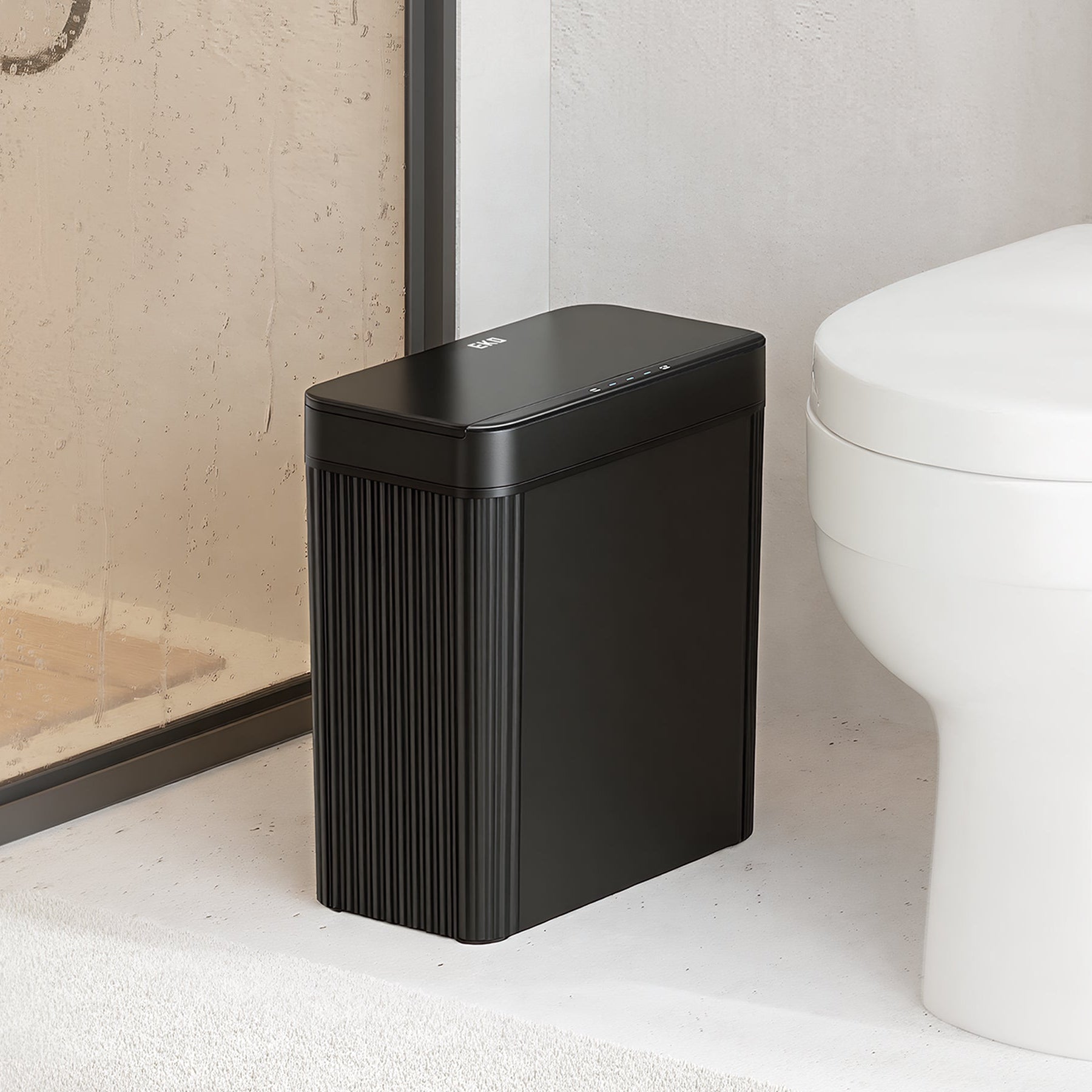 Black rectangular trash can on a bathroom floor next to a toilet