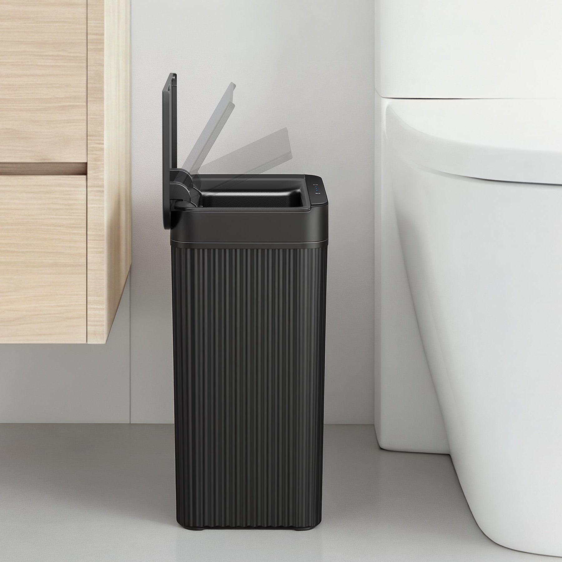 Black trash can next to a white toilet in a bathroom setting