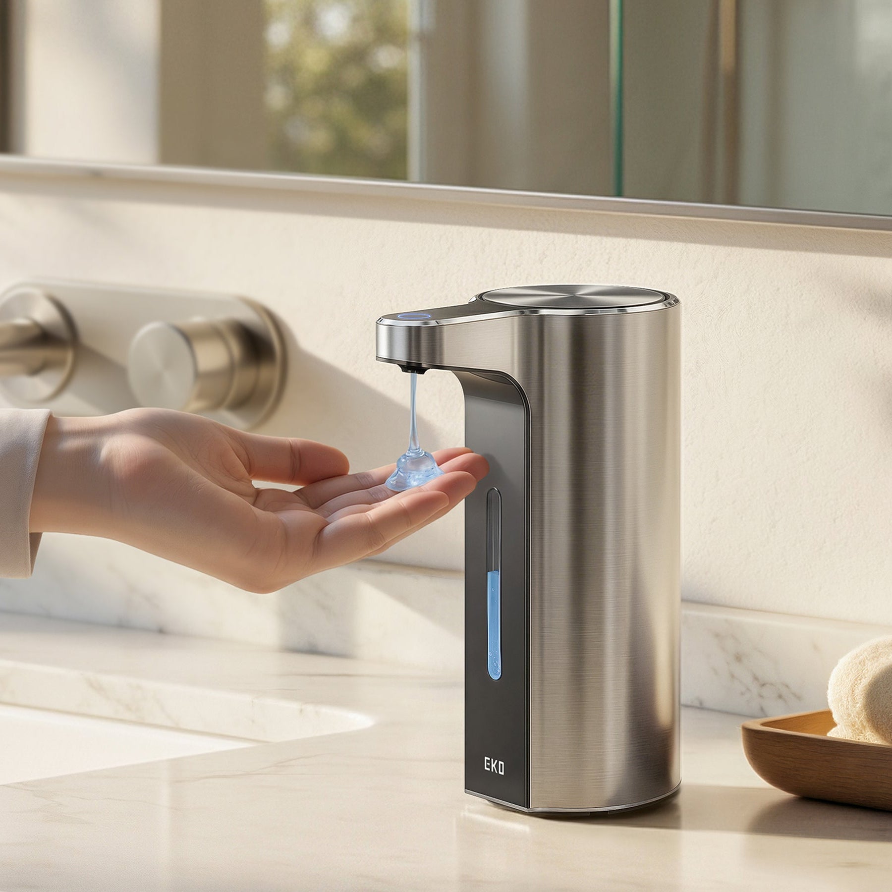 Person using a stainless steel soap dispenser on a bathroom counter.